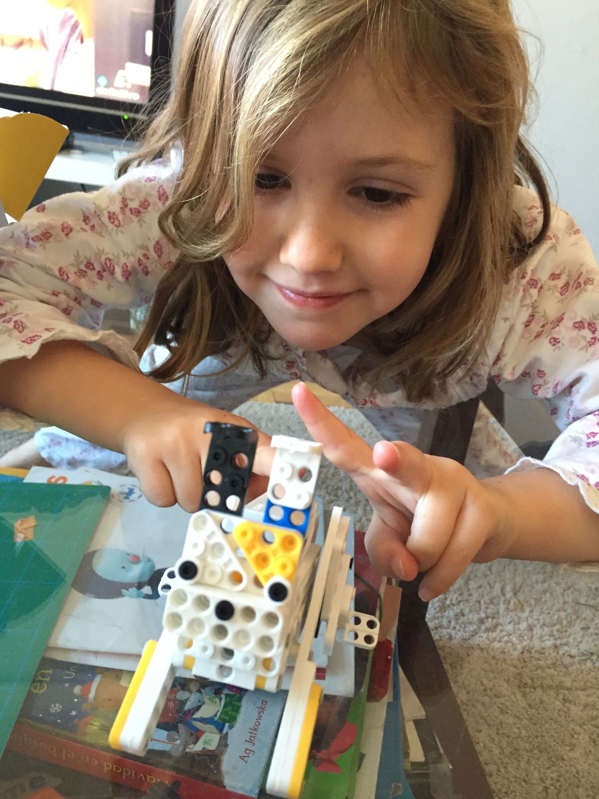 Pointing at a white robot I built with black, blue and yellow pieces