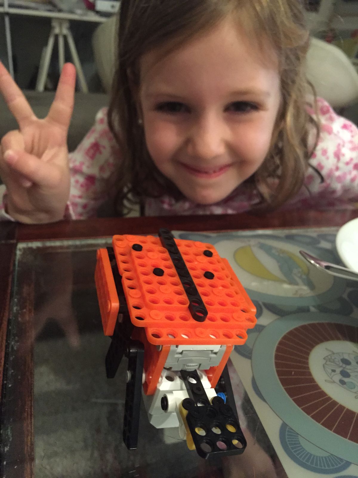 Making a peace sign behind an orange robot ladybird