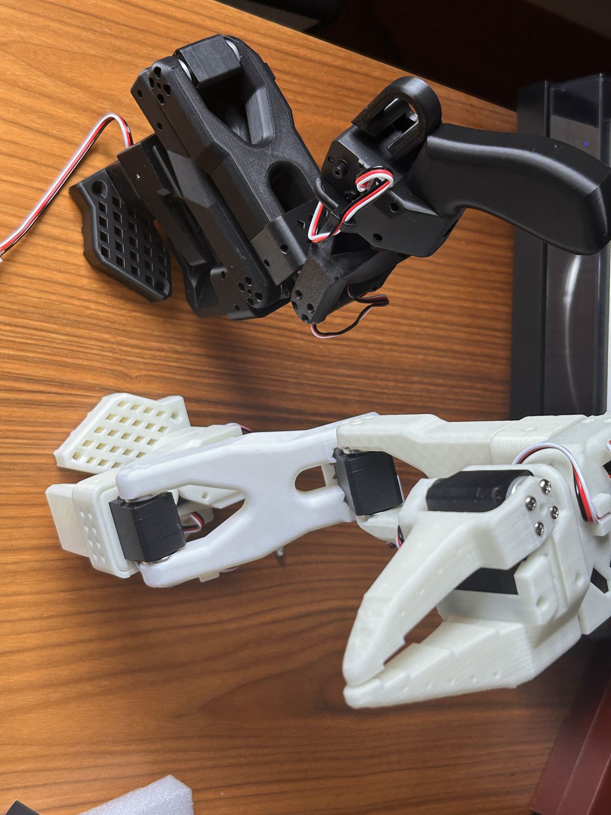 Both arms on the table: the black leader and the white follower with its gripper